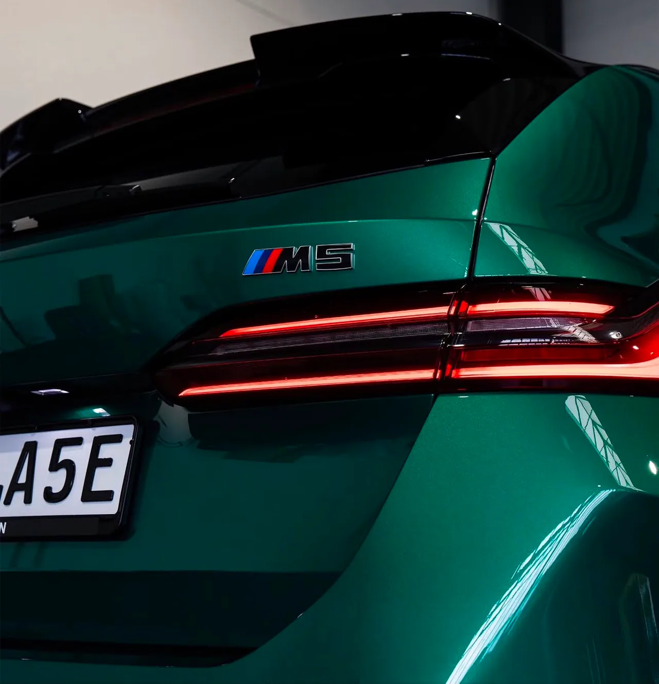 Heckdetail eines grünen BMW M5 mit spiegelndem Lack