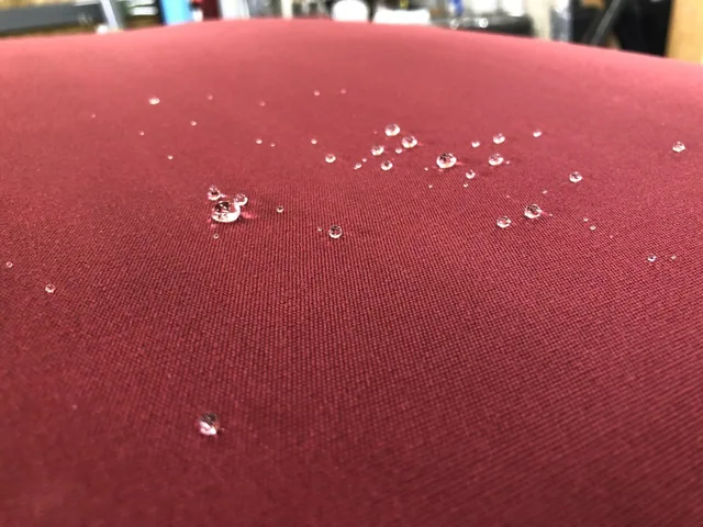 Wassertropfen perlen von einem roten Cabrioverdeck ab